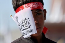 Chlapec predáva vlajky Islamského emirátu Afganistan počas osláv piateho výročia návratu Talibanu, ktoré sa v Kábule konali 15. augusta. FOTO: Reuters